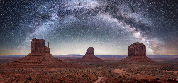 Night sky with the arch of the milky way showing on a dramatic sky above the towering sand stone buttes at Monument Valley. Located on the Arizona and Utah border of the southwest USA.