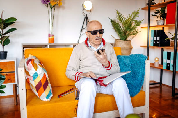 istock Blind old man having a call on mobile phone in living room 1483084580