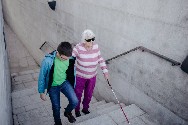 istock Child supporting blind old person with climbing stairs and walk 1483084612