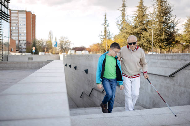 istock Child supporting blind old person with climbing stairs and walk 1483084643