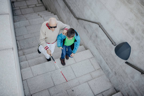 Child supporting blind old person with climbing stairs and walk