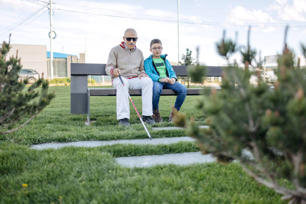 istock Old person with disability spending time with grandson sitting on the bench in public park 1483084657