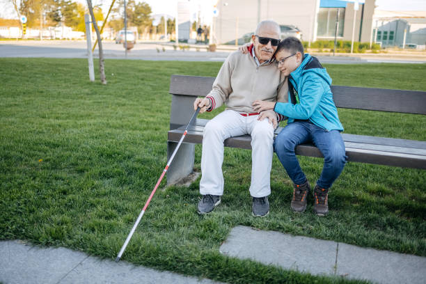 istock Old person with disability spending time with grandson sitting on the bench in public park 1483084665