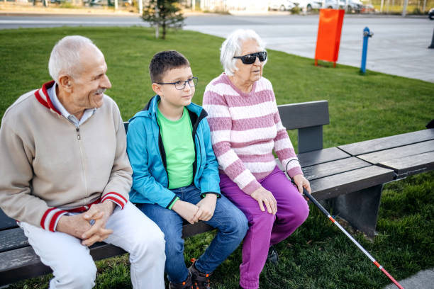 istock Old person with disability spending time with grandson sitting on the bench in public park 1483084695