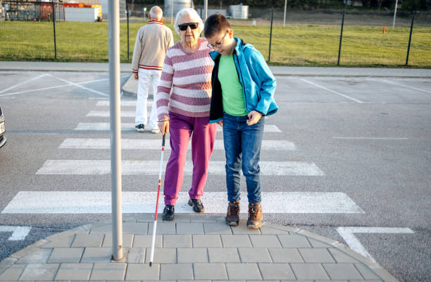 istock Kid support old person with disability to cross street 1483084816