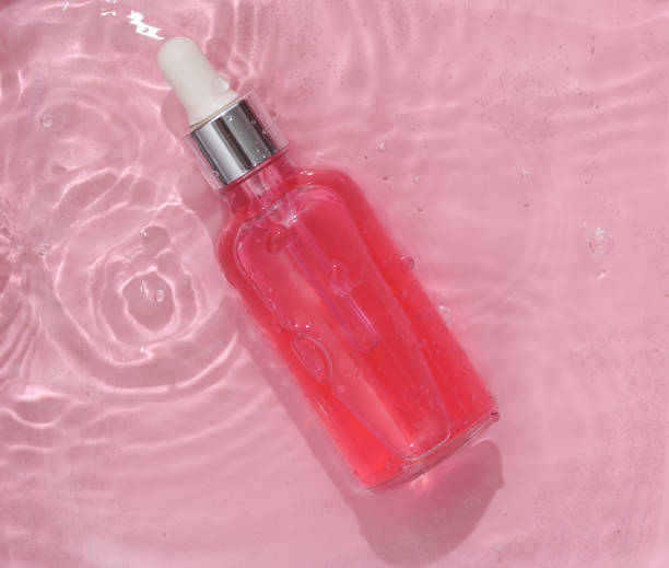 istock Pink serum bottle in pink water with shadows. Beauty concept. Top view 1483086115