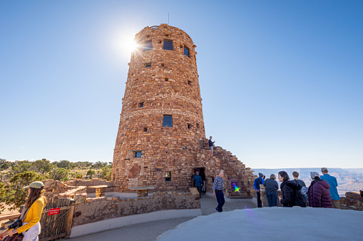 Grand Canyon, United States - October 14, 2018: Group of tourist watching, taking photos at Desert view Watchtower point of dramatic rock landscape,  view over the Grand Canyon, with blue clear sky, Arizona, USA.