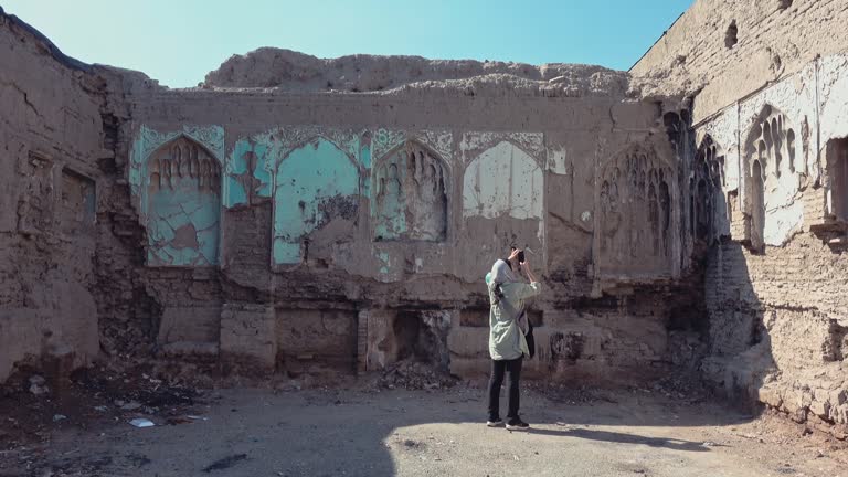 A young Persian girl is taking a photo of the remains of an ancient building