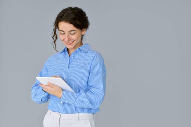 istock Young smiling professional business woman using digital tablet isolated at gray. 1483090247