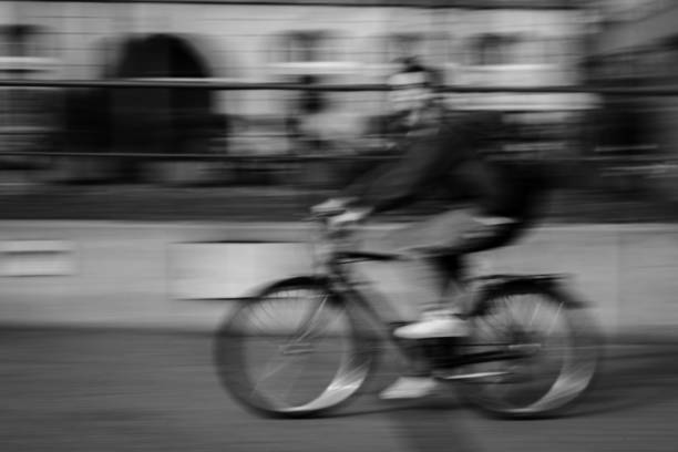 Young student driving bicycle at high speed through the city. Heavy motion blur. photographic sweep. Black and white.