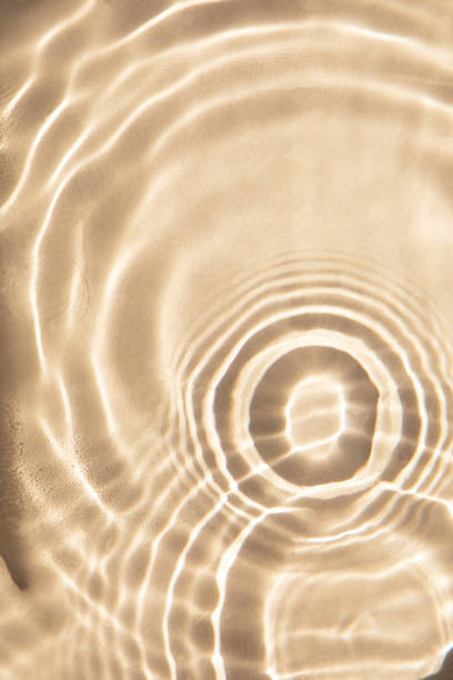 istock Abstract nature textured background, water waves with sun reflection. Clear water with bubbles and circles on beige background 1483091745
