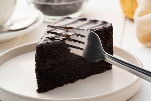 Delicious Sliced of Classic Chocolate Cake with fork on white plate