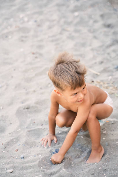 istock Little boy wearing diaper is playing on sandy beach during summer vacation 1483093641