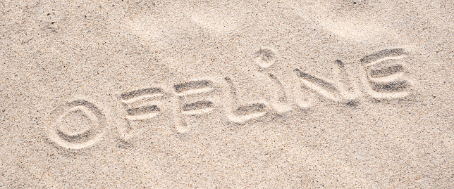 Sand background. Word Offline written on sand.