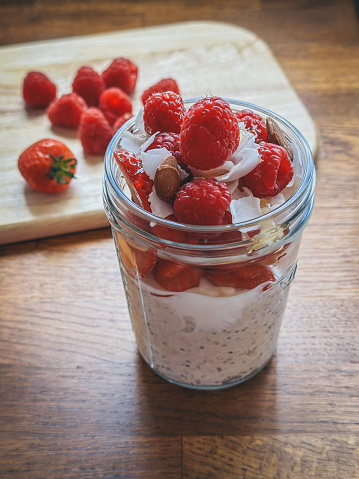 Overnight oats in glass jar with  berries, coconut flakes, almonds and honey toppings