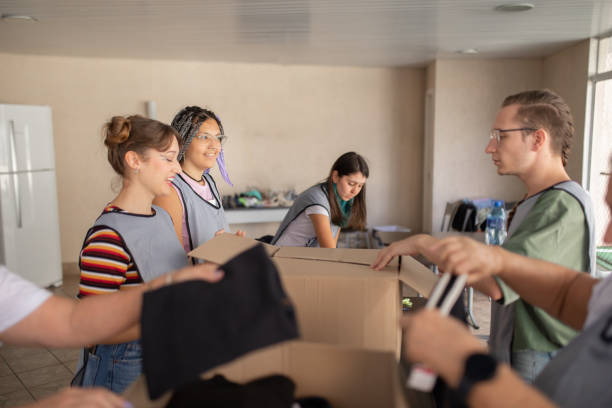 istock Young group of friends doing volunteer work filling boxes with clothes 1483099435