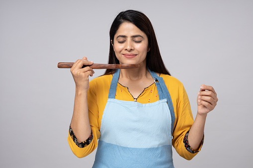 Portrait of Indian women chef standing isolated over gray background