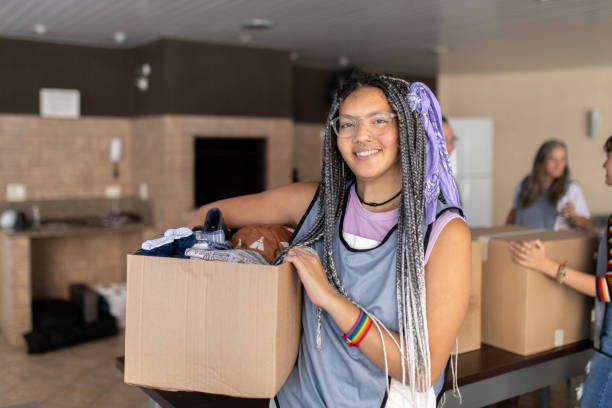 Young girl smiling while holding a box full of clothes