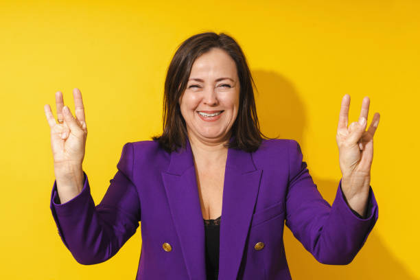 istock Cheerful middle aged woman showing finger gesture against yellow background 1483099636