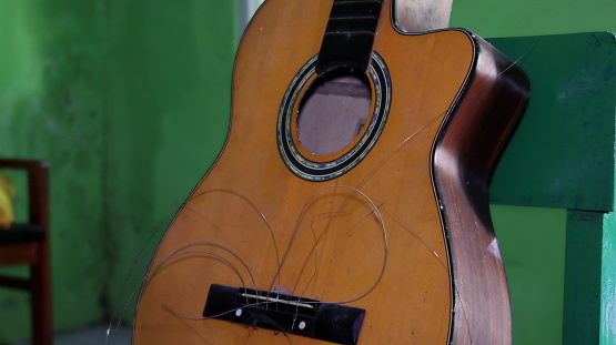 Broken brown classical guitar. Strings of classical guitar broken. Old grungy guitar