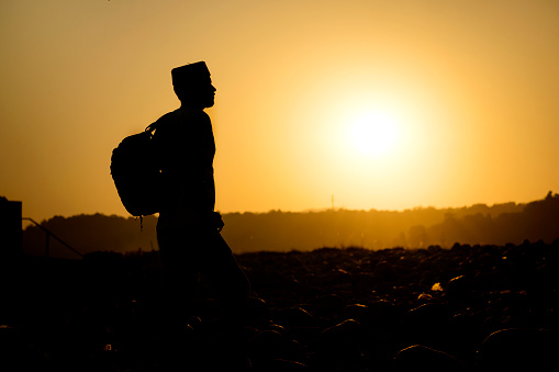 Silhouette image of an Indian young man enjoying the beautiful view of sunset in the mountains.