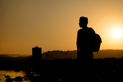 Silhouette image of an Indian young man enjoying the beautiful view of sunset in the mountains.