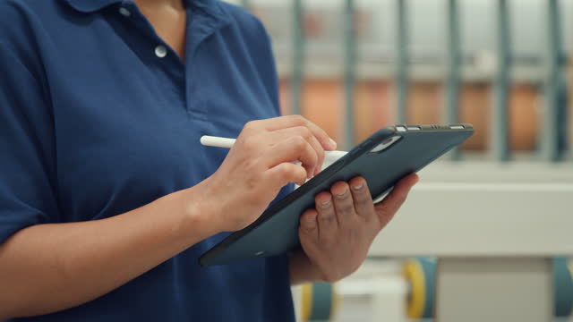 Closeup of professional female industrial engineers use tablet while standing in manufacturing factory. Working in manufacturing plant or production plant.