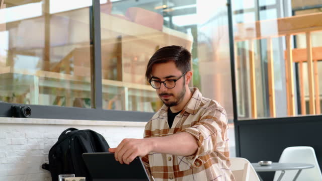 Man preparing to work with digital tablet at coffee shop table