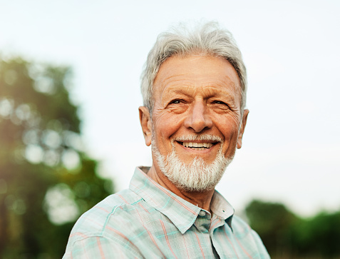 Portrait of an elderly man outdoors. Happy senior man in park
