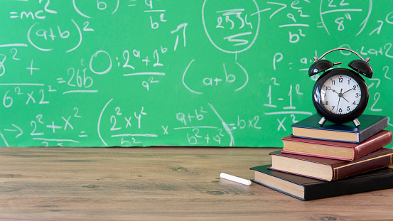 Education concept - books on the table in the auditorium. blackboard back to school