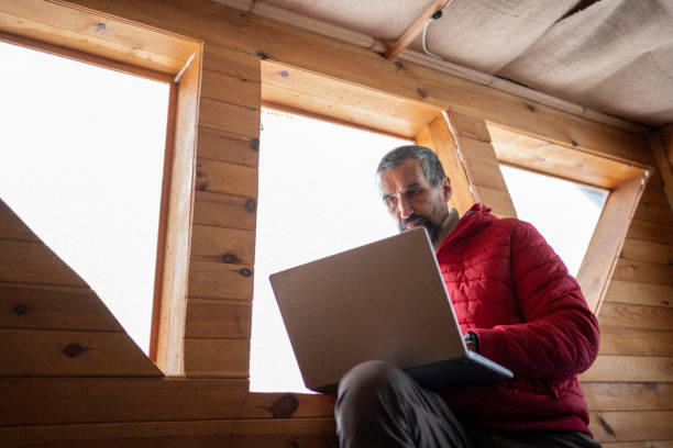 istock Cabin getaway. Man with laptop in log cabin. 1483117157
