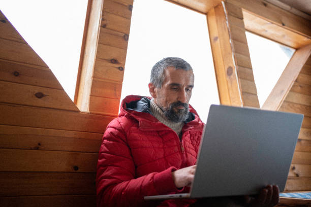 istock Cabin getaway. Man with laptop in log cabin. 1483117160