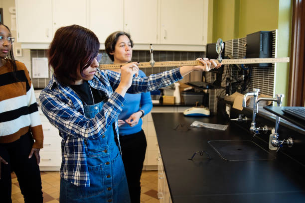 Girls in STEM, student holding a basic telescope under teacher supervision.