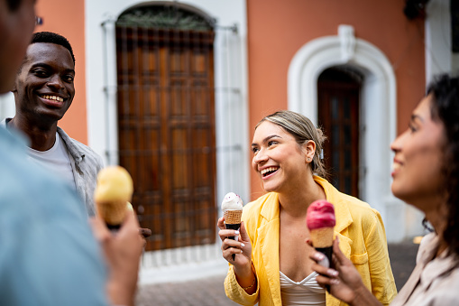 Young couple eating ice cream with friends outdoors