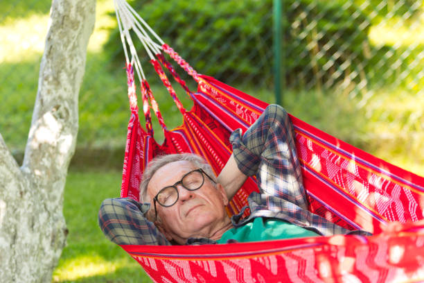 istock Tired senior man with hands behind head sleeping in hammock 1483120508