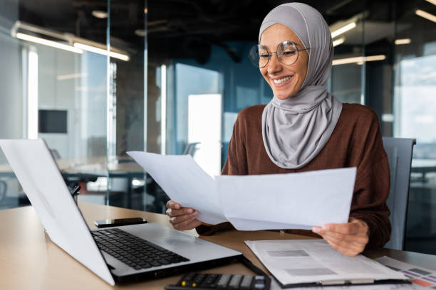 istock Successful muslim woman in hijab working inside office with documents, joyful financial accountant happy with reports checking financial data and smiling, businesswoman at workplace with laptop 1483120872