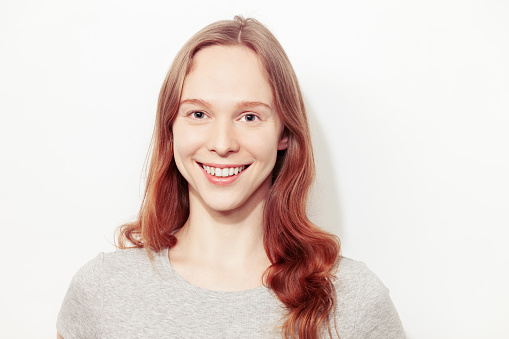 Close-up studio portrait of a happy white young woman with long brown hair against a white background