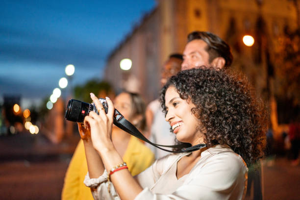 Young woman taking pictures with friends on the city by the night