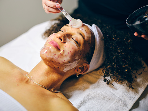 A young woman in a day spa, receiving a facial treatment.