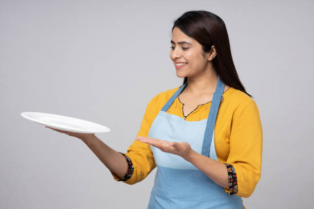 istock Smiling female chef holding empty plate stock photo 1483122380