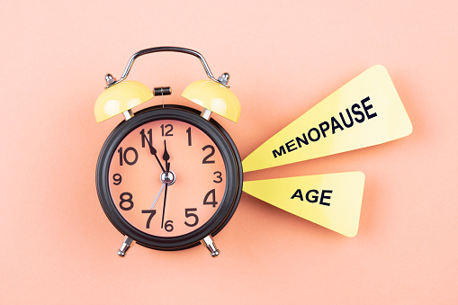 Alarm clock and papers with text Menopause age