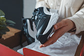 Unpacking women's shoes, stylish white sneakers in hands