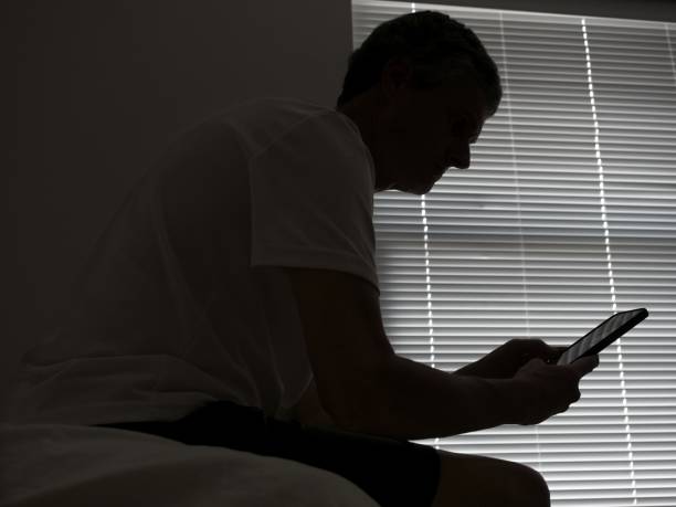 istock A man sits in a dark room interacting with his smartphone 1483132543