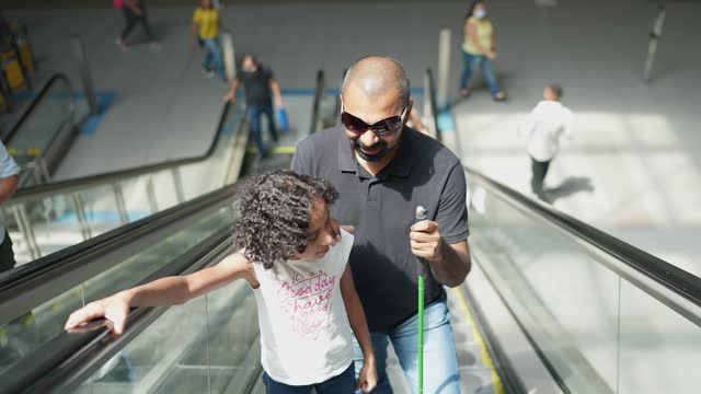 Blind father and daughter talking at a subway station