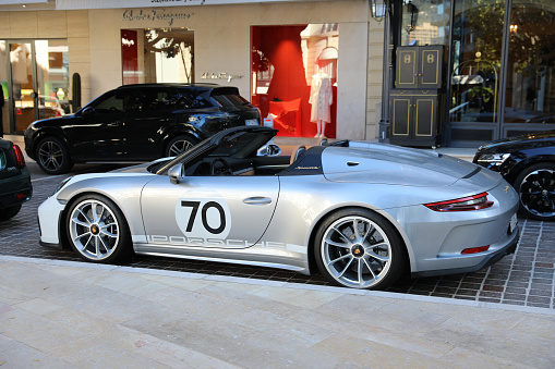 Monte-Carlo, Monaco - April 16, 2023: Side view of gray and white Porsche Speedster race car, featuring a prominent number 70 sticker on the door, parked at the luxurious Hermitage Hotel in Monte-Carlo, Monaco