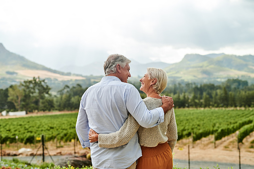 Senior couple hugging and smiling at each other in vineyard