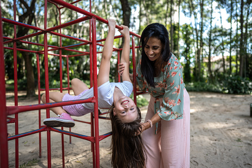 Portrait of a girl playing in a jungle gym with her mother at the park