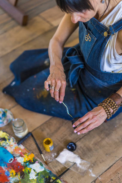 mujer artista pintando sobre un lienzo una pintura abstracta azul. mujer creativa trabajando en el suelo de su estudio de arte. - oil painting painted image art studio fun fotografías e imágenes de stock