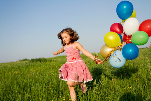 little girl runs with multicolored balloons