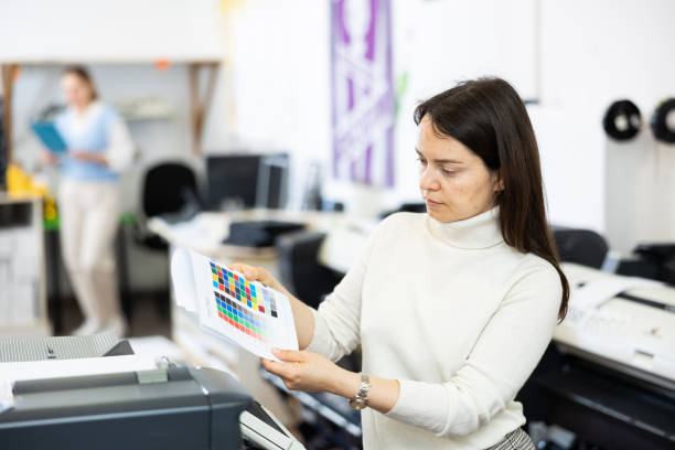 gerente de la oficina de impresión mirando la página de prueba de color para la impresora - printout industry store workshop fotografías e imágenes de stock